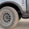 Close-up side photo showcasing the FOX Performance Elite Series 2.5 shock absorber installed on a 2021 Ford Bronco, behind the front wheel. The photo highlights the prominent appearance of the shock absorber due to its shiny silver body.