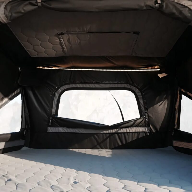 The interior of the Rock Cruiser tent with a soft-looking honeycomb-patterned mattress across the floor. Huge windows allow for a bright environment, with lots of light making it inside.