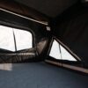 Image of the interior of the car rooftop tent, which can accommodate 2 to 3 people. It has a lot of space, and a large LED strip about two fingers wide, that expands across the ceiling parallel to the entrance.