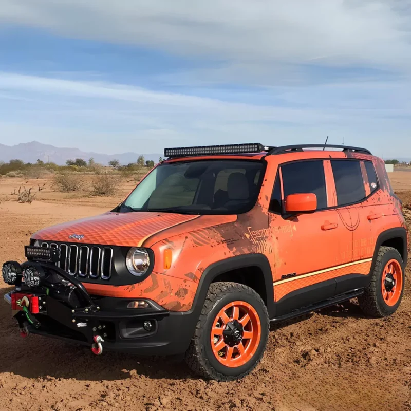 Right side view image of an orange Jeep Renegade lifted 40mm, on the sand.