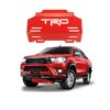 A front view of the Red Steel Engine Skid Plate with 8 airflow channels and the TRD logo, with a Red Hilux Revo. The image shows that this engine guard is eye catching even from afar.