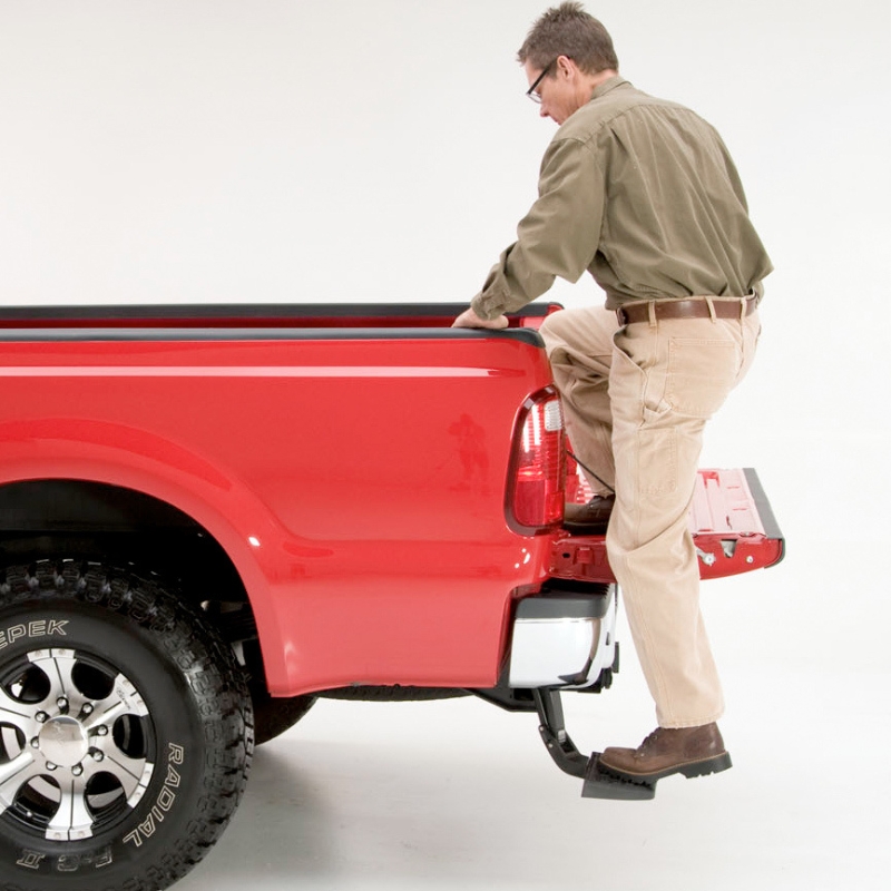 Image showing a man stepping on the trunk bed with the help of the Toyota Hilux 2015+ Retractable Rear Bumper Steel Step