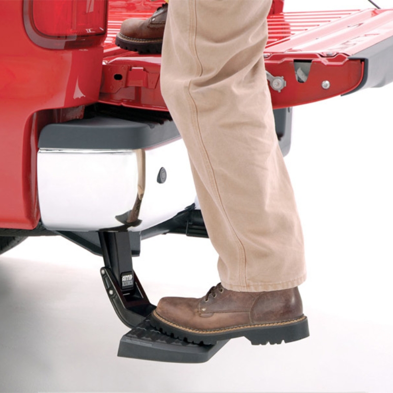 Close-up image of a man stepping on the trunk bed with the help of the Toyota Hilux 2015+ Retractable Rear Bumper Steel Step