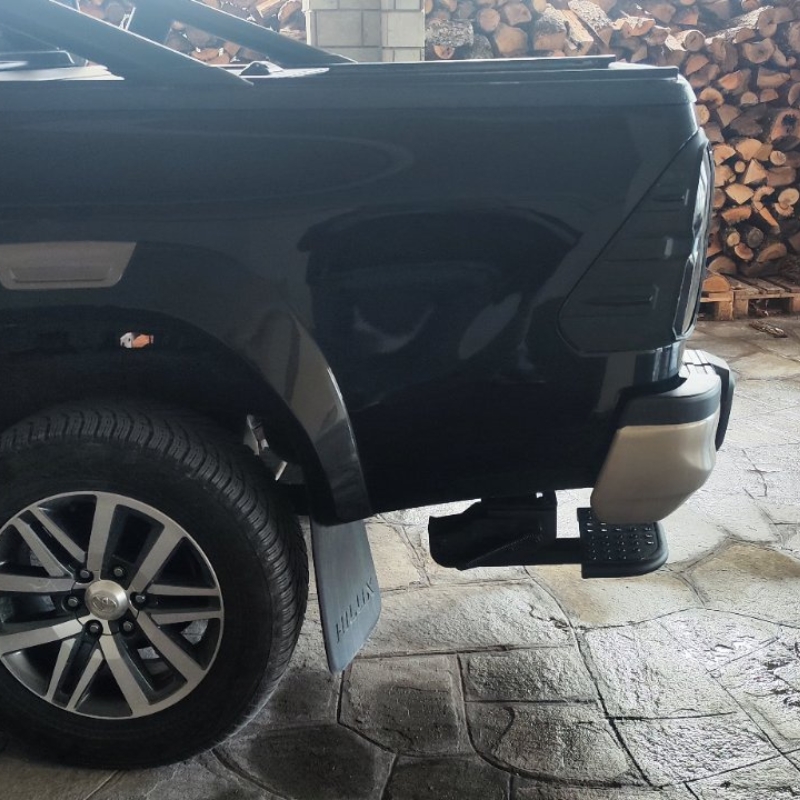 Image showing the Toyota Hilux 2015+ Retractable Rear Bumper Steel Step folded and installed on the rear bumper.